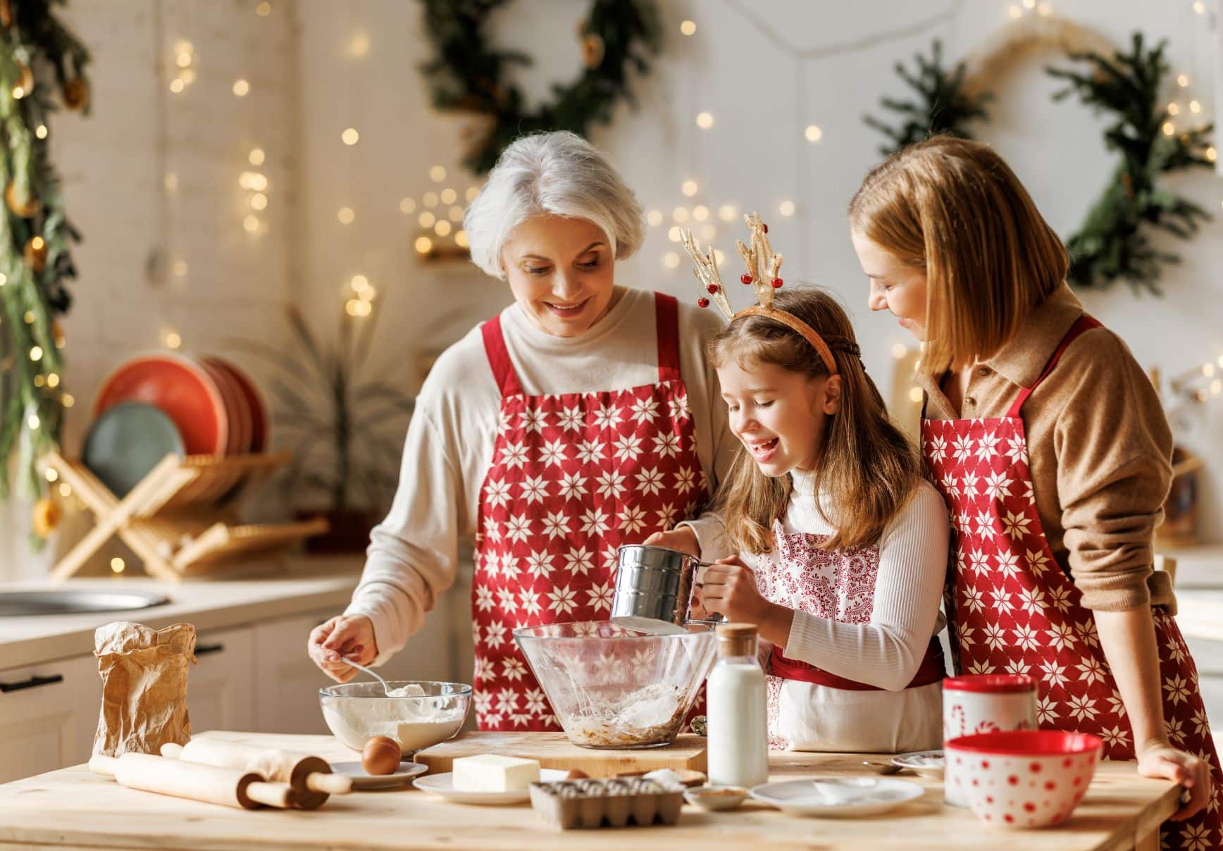 elderly woman, adult woman, and young girl baking cookies together