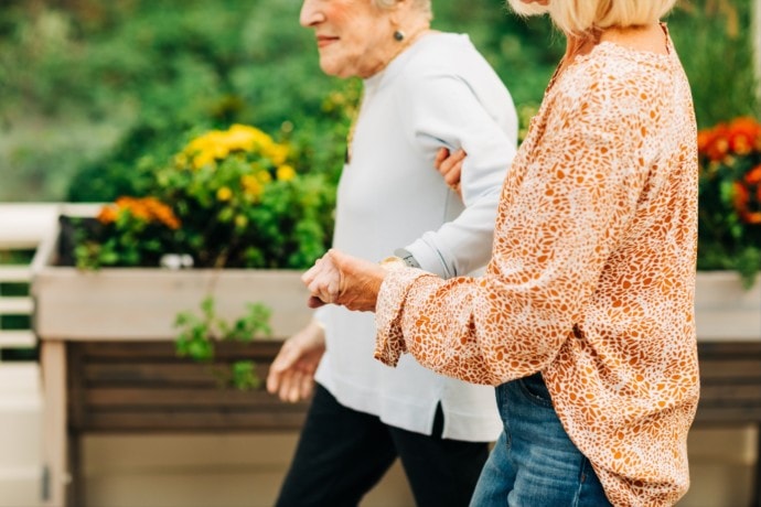 elderly woman walking with younger adult woman in garden