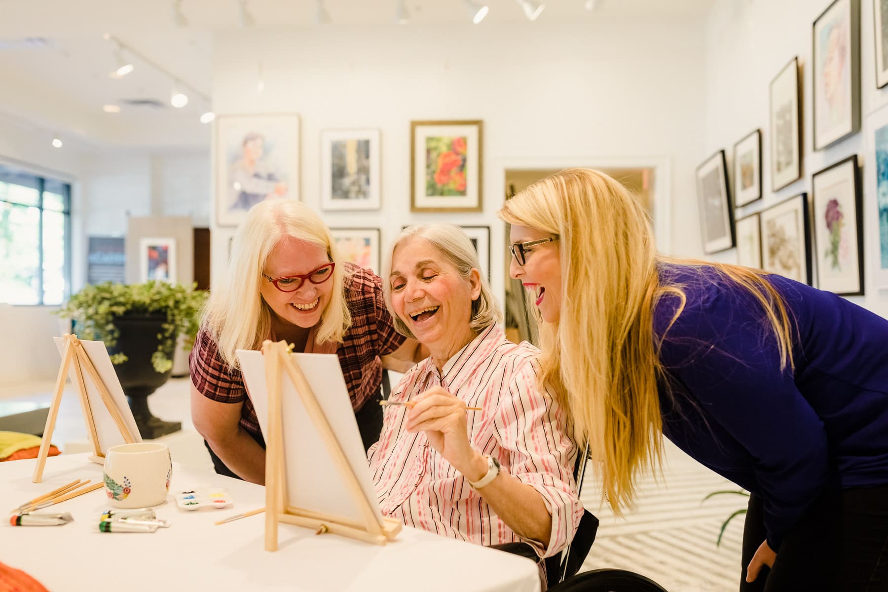 elderly woman with daughter and granddaughter painting easel