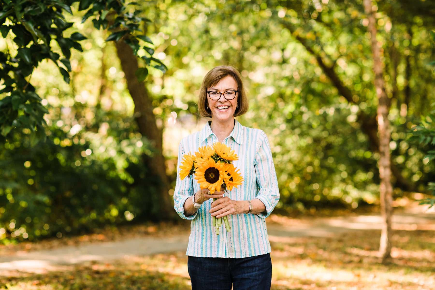 elderly woman holding sunflower outside