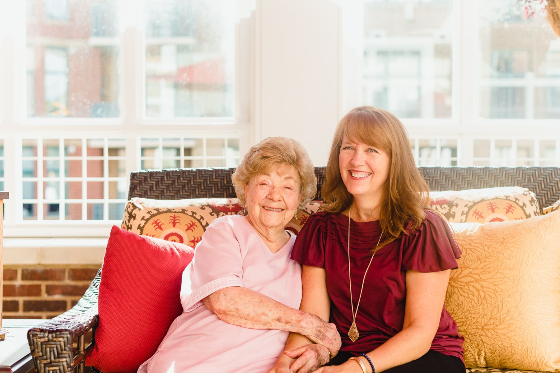 elderly mother and daughter smiling on couch