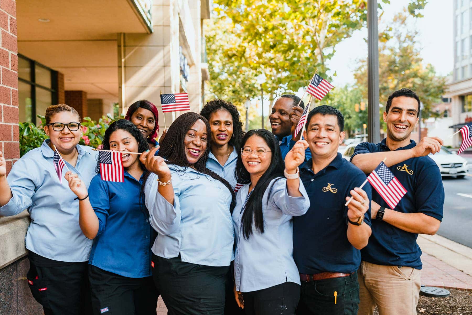 team members holding american flags and smiling outside