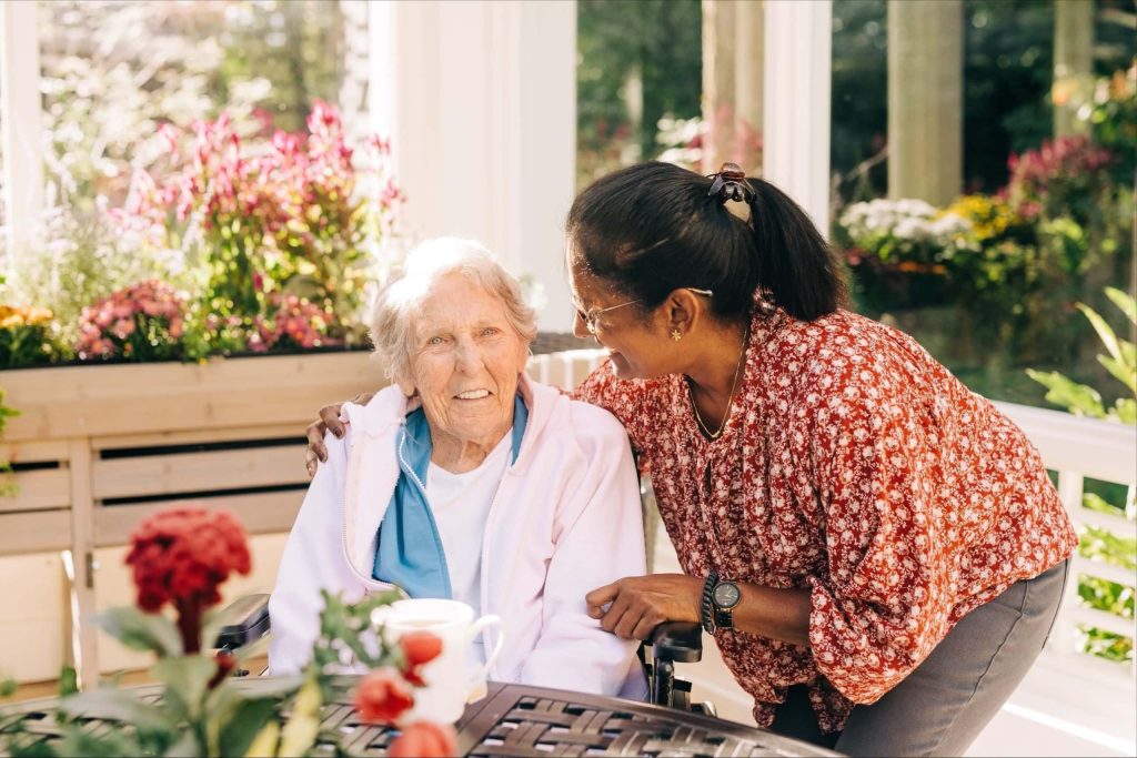 elderly woman sitting with younger adult woman in garden