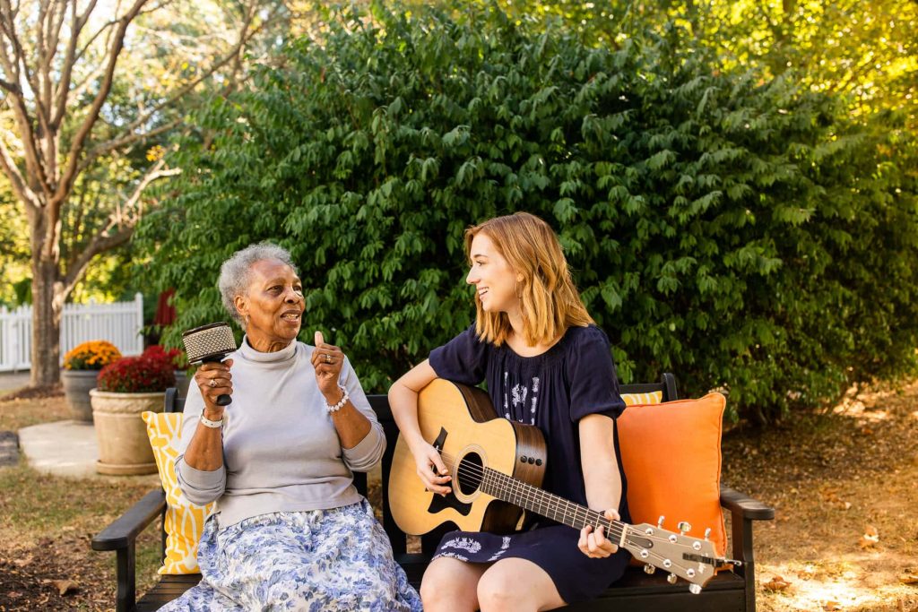 music therapist playing guitar and elderly woman singing