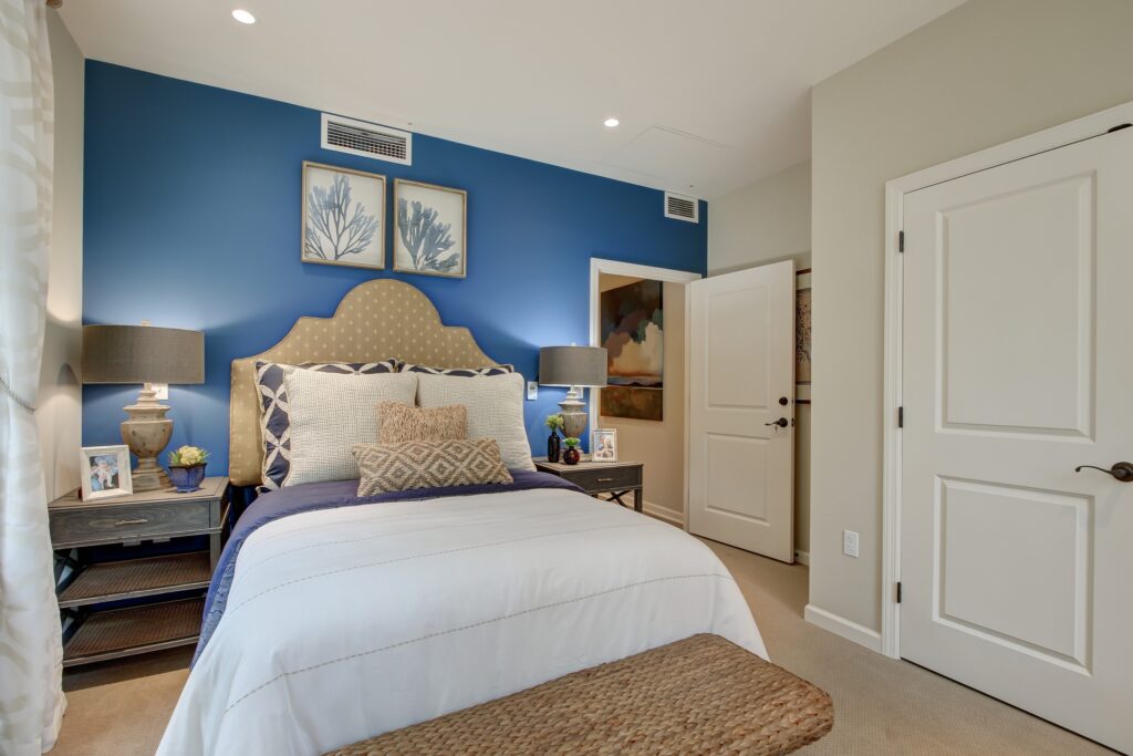 A bedroom with a bed, dresser, and window.