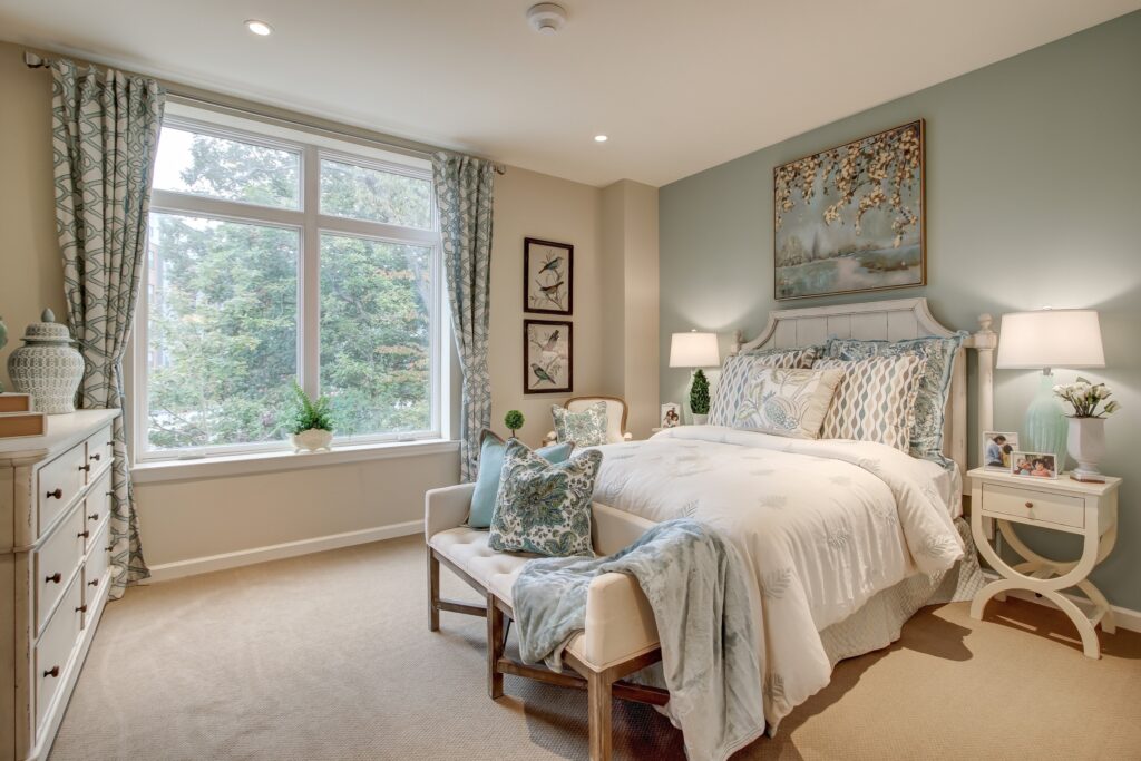 A bedroom with a bed, dresser and window.