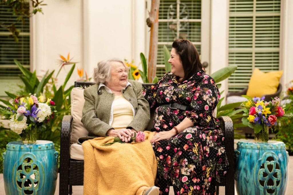 caregiver and elderly woman sitting on bench together