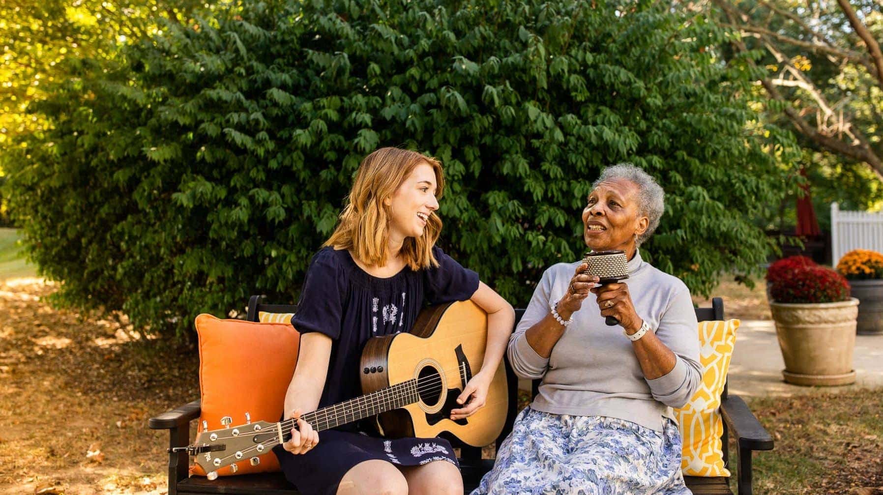 music therapist playing guitar and singing with elderly resident