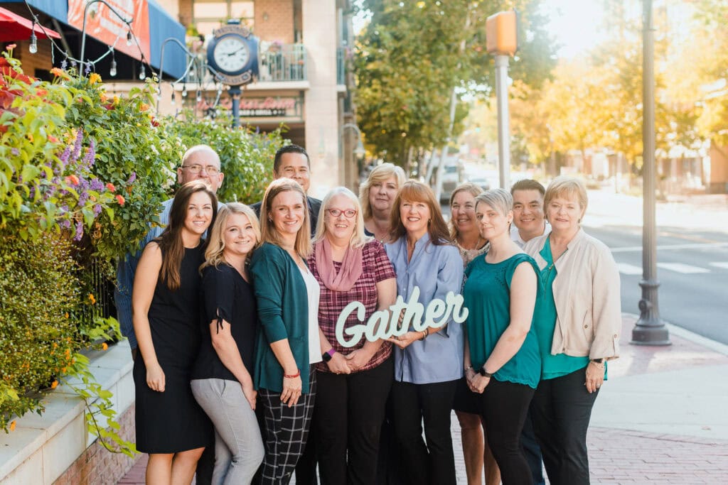 group of men and women holding sign that says gather